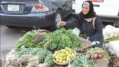 سيدة تبيع شبت وبقدونس على ظهر قفص مقلوب على اﻷرض
